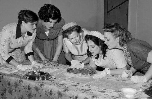 Black and white photo of five ladies in 1940s clothing examining a silver platter.
