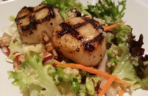Grilled scallps on a bed of lettuce salad.
