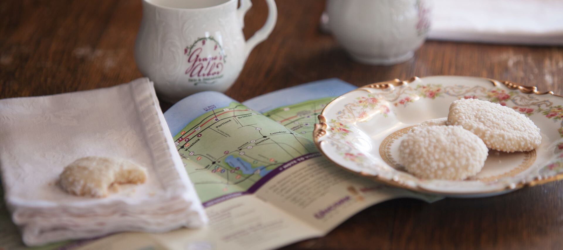 Cookies on a china plate with a map and two cups of coffee