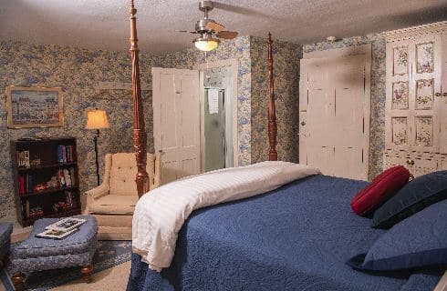 Guest room with patterned wallpaper and a cozy sitting area with two chairs